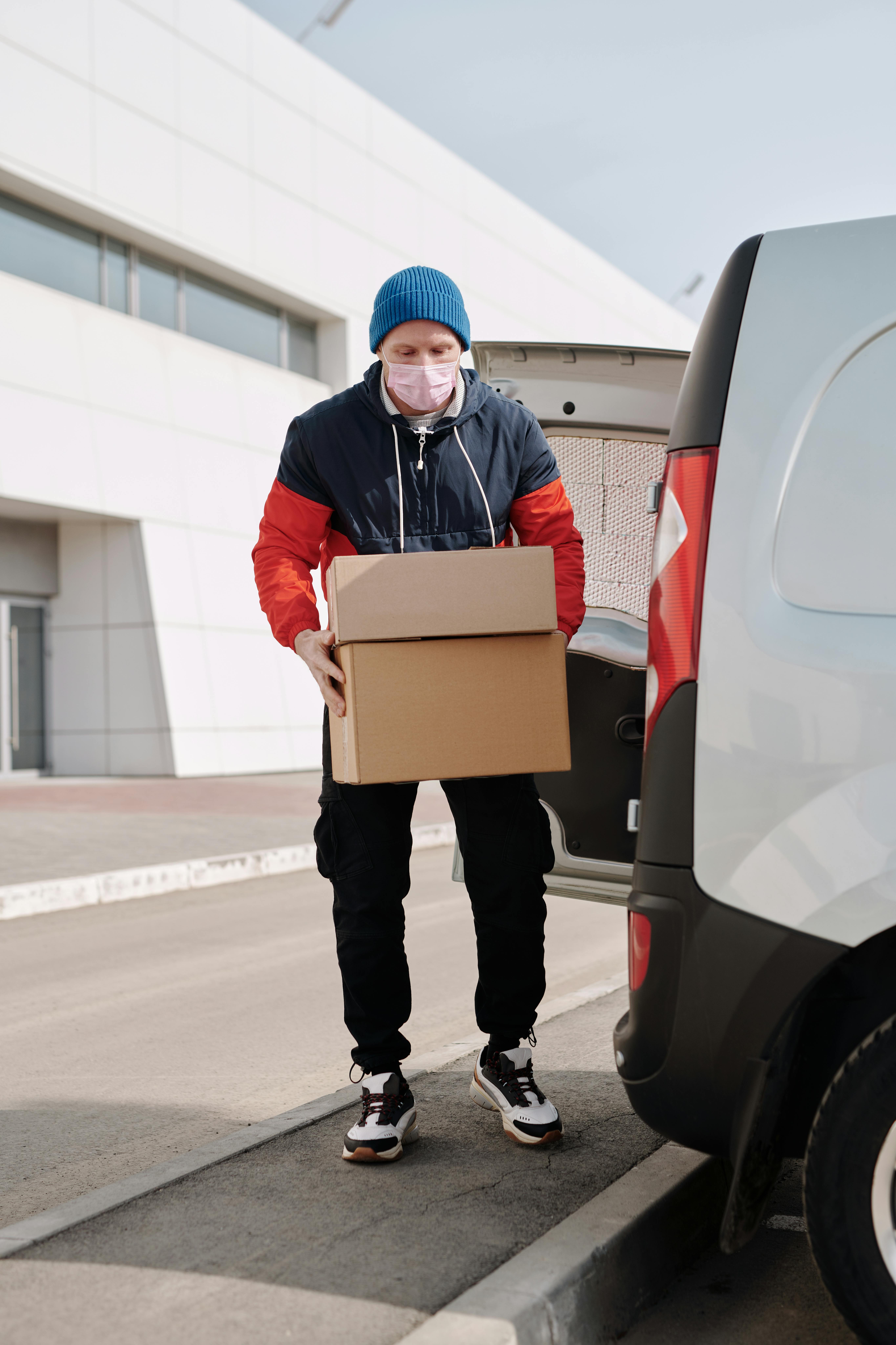 JetBlack Freight 7 A delivery worker wearing a face mask unloading packages from a van in an urban area.